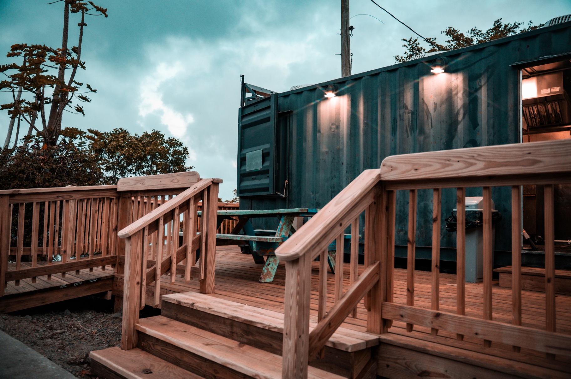 Twilight on the Drifters deck — picnic tables, warm wood, and moody Caribbean sky